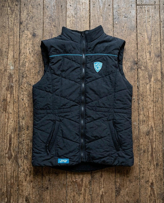Black puffer vest with a brand logo on a wooden surface